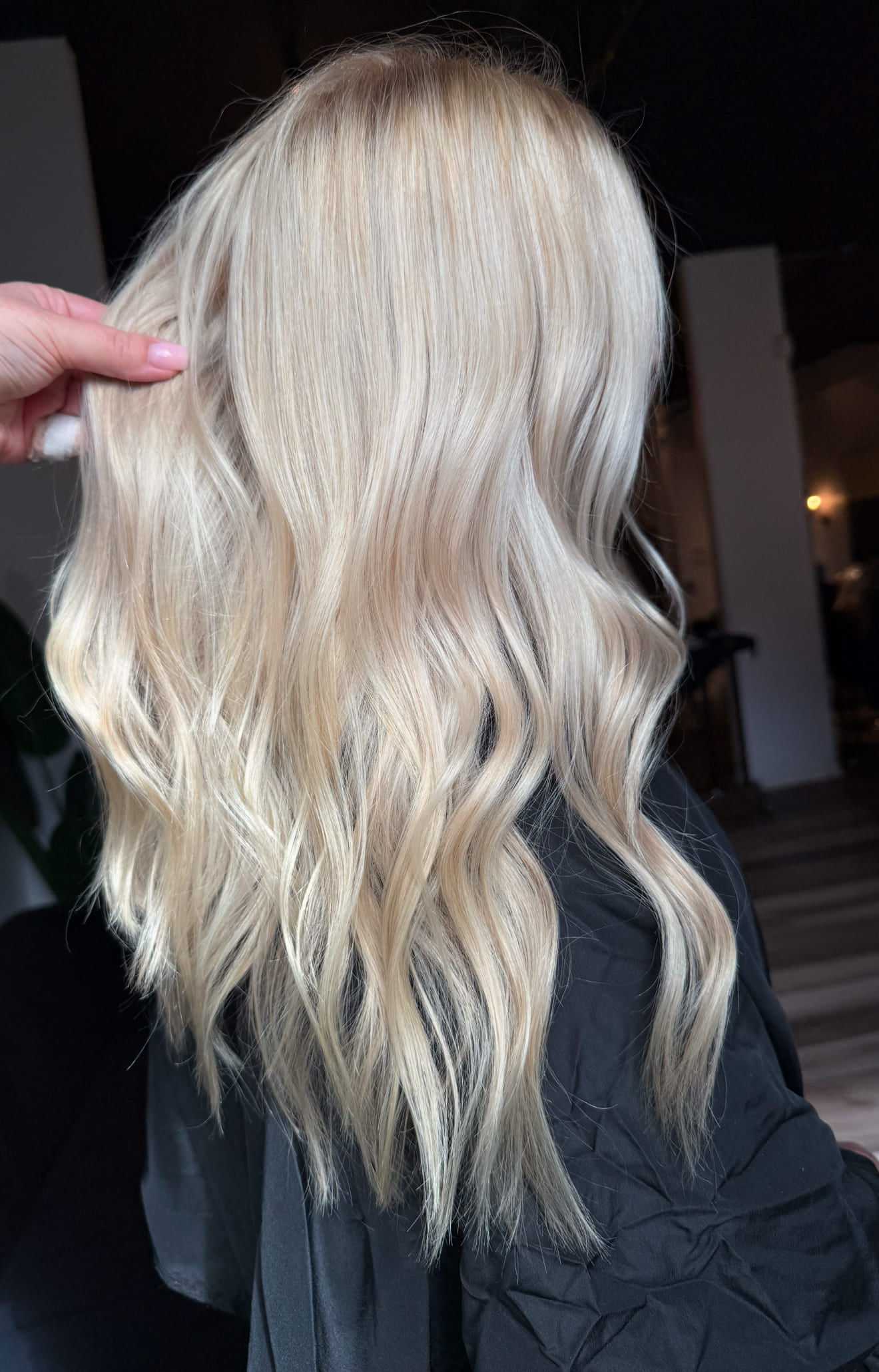 Wavy blonde hair styled elegantly, viewed from the side in a salon setting.